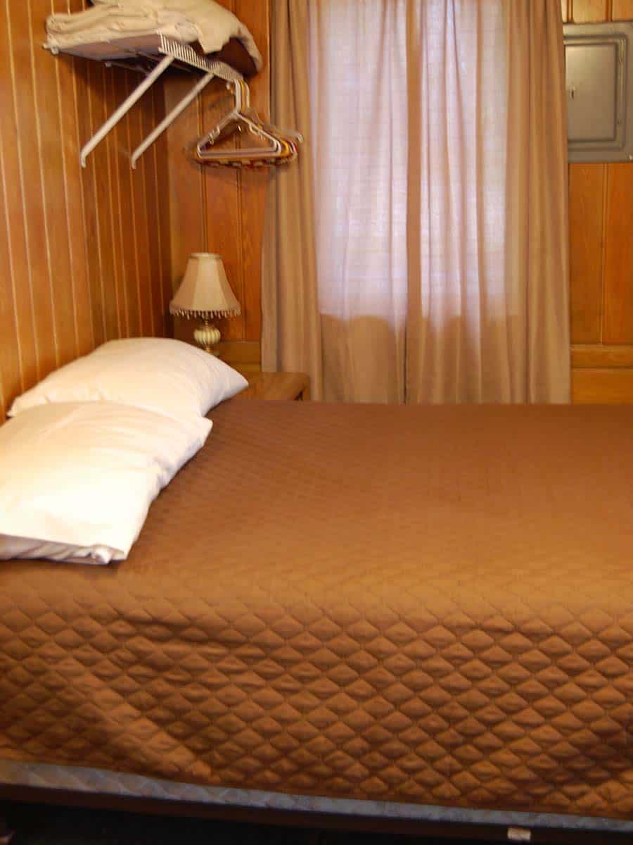 A Bed With A Lamp And Hanger In A Room